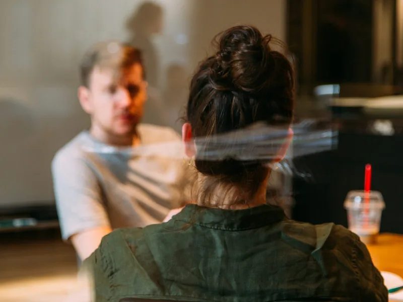 Dos personas conversando frente a una mesa.