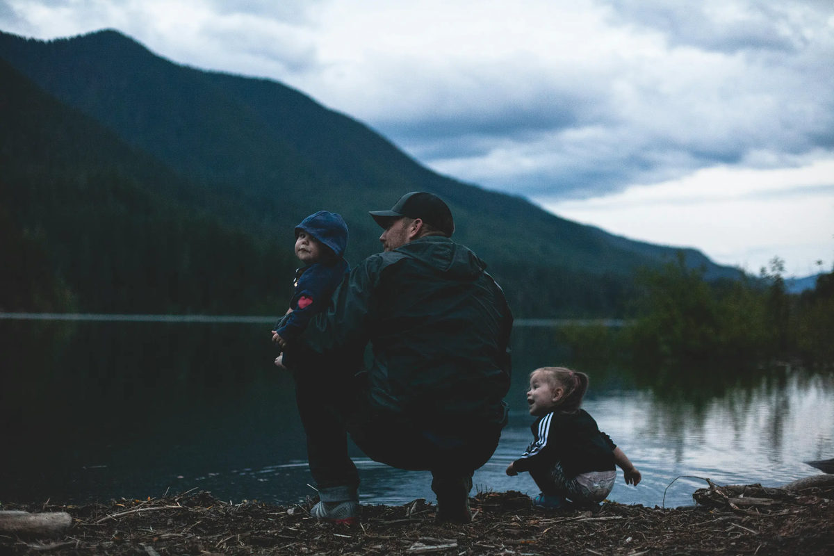 Adult and two children beside a mountain lake