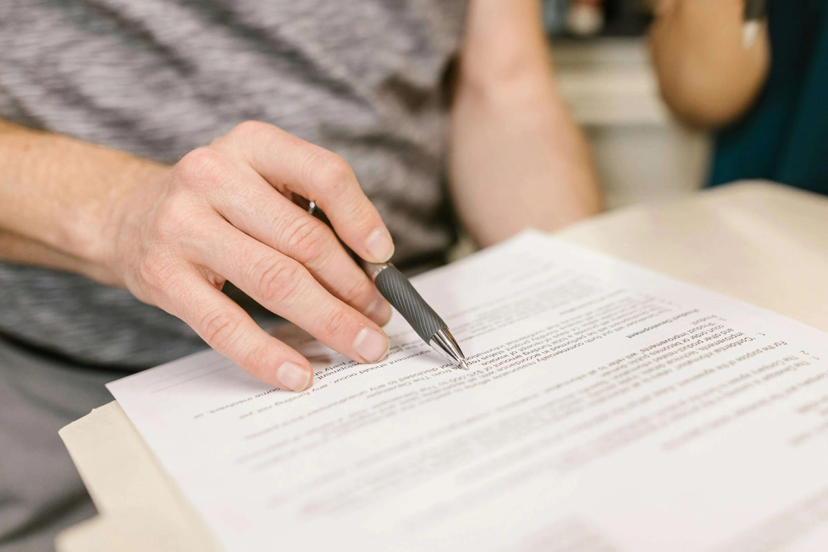Mano sosteniendo un bolígrafo sobre un documento impreso.
