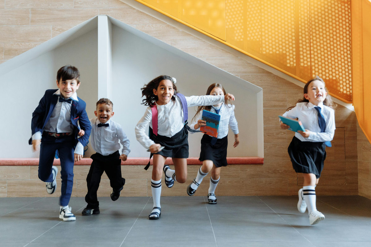 Children carrying schoolbags in a hallway