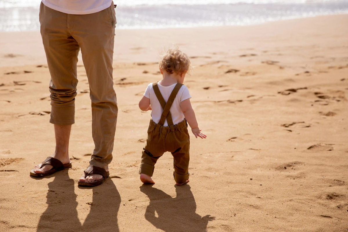 Adult and toddler walking along a beach