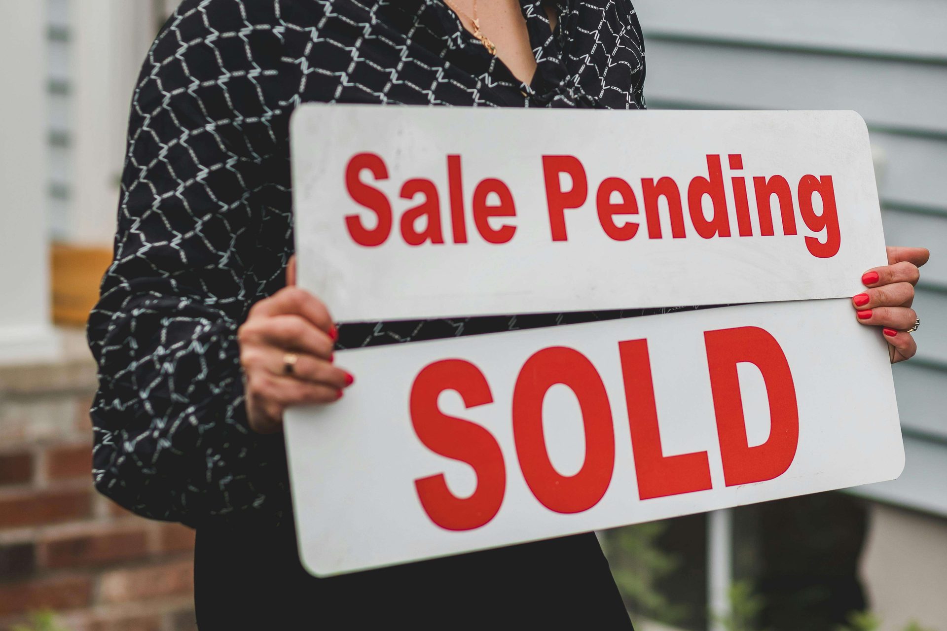 Person holding a Sale Pending and Sold sign